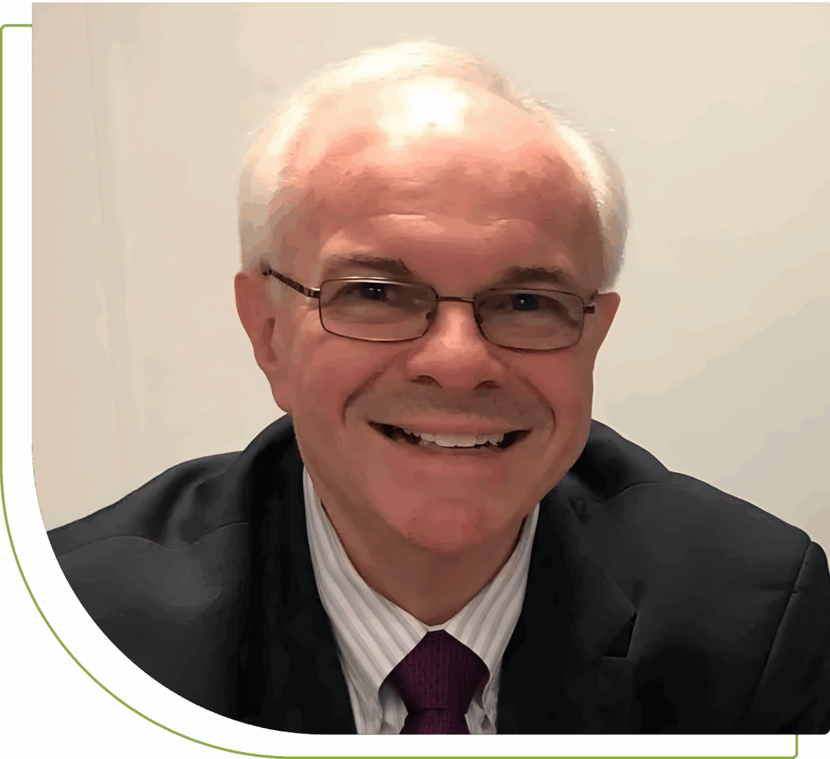Smiling elderly man with white hair and glasses in a suit.