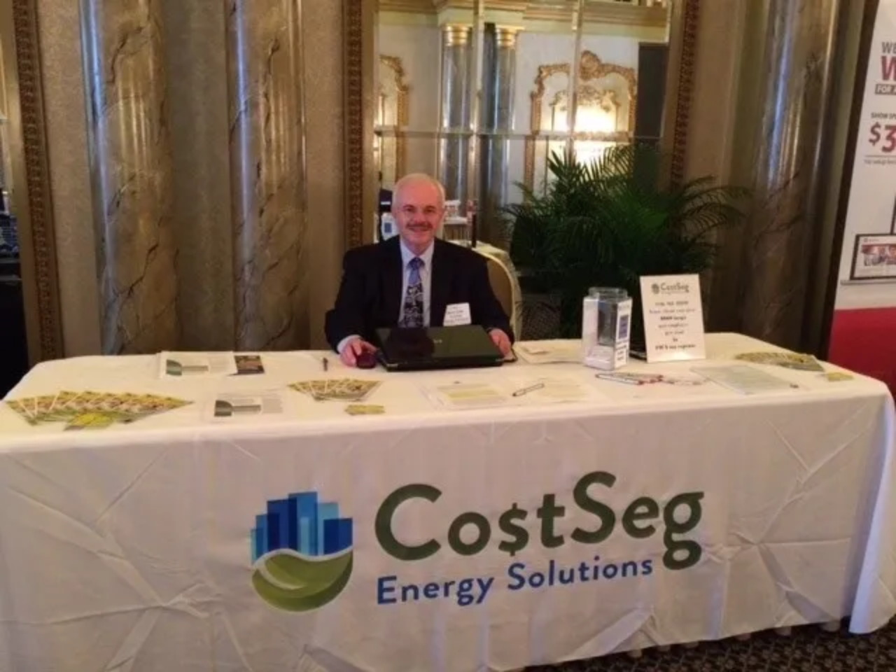 Man sitting behind a CostSeg Energy Solutions table at an event.