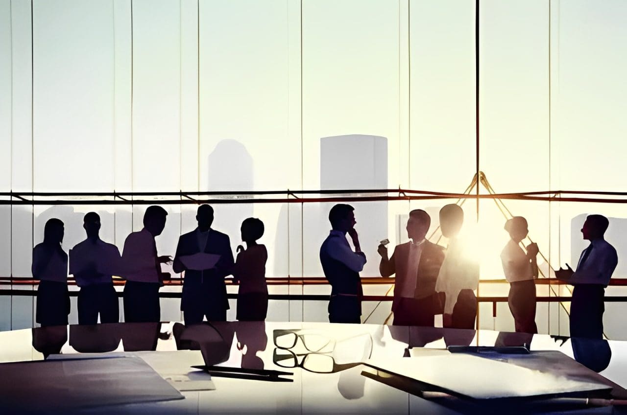 Silhouetted professionals networking in a modern office at sunset.