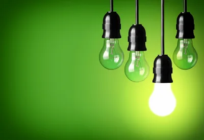 Three hanging light bulbs with one glowing against a green background.