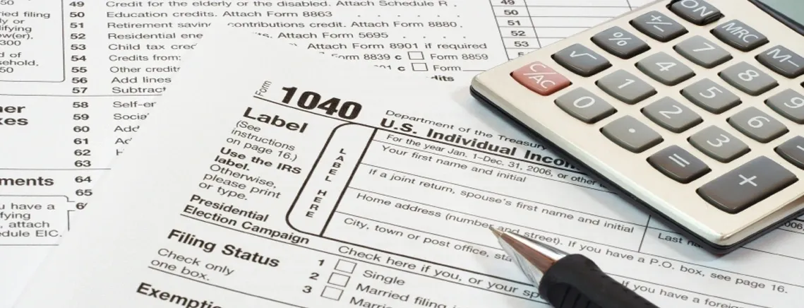 Close-up of a 1040 tax form with a pen and calculator on paperwork.