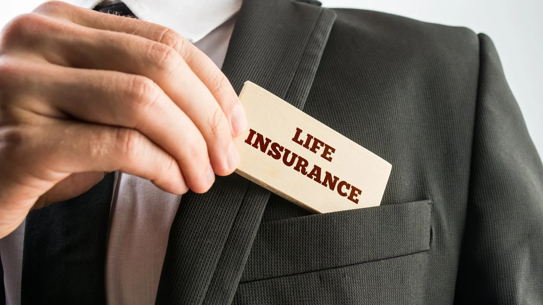 Person placing a life insurance card in a suit pocket.